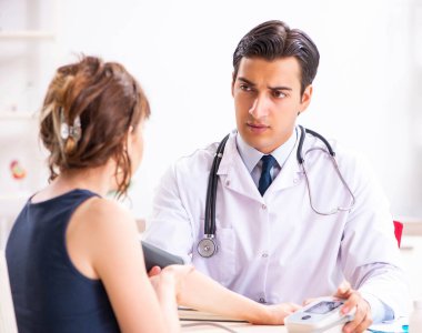 Genç doktor, kadınların tansiyonunu ölçüyor.