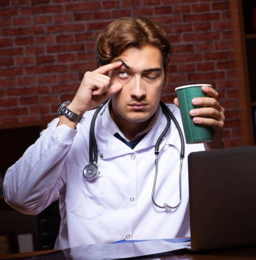 Genç yakışıklı doktor gece hastanede çalışıyor.