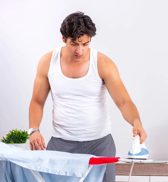 Junger Mann bügelt im Schlafzimmer — Stockfoto