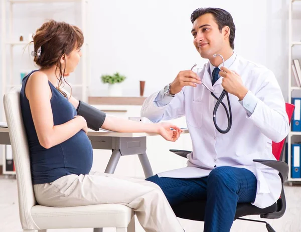 Terhes nők vérnyomását ellenőrző fiatal orvos — Stock Fotó