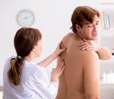 Genç bayan doktor kayropraktör erkek hastaya masaj yapıyor.