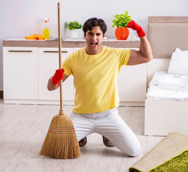 Giovane uomo bello pulizia in camera da letto — Foto Stock