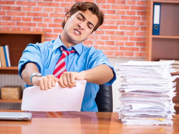 Young employee with excessive work sitting at the office — Stock Photo, Image