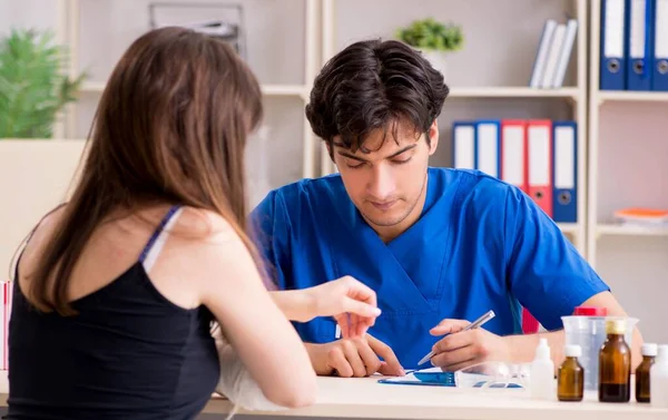 Kolu bandajlı genç kadın erkek doktor traumotologis 'i ziyaret ediyor.