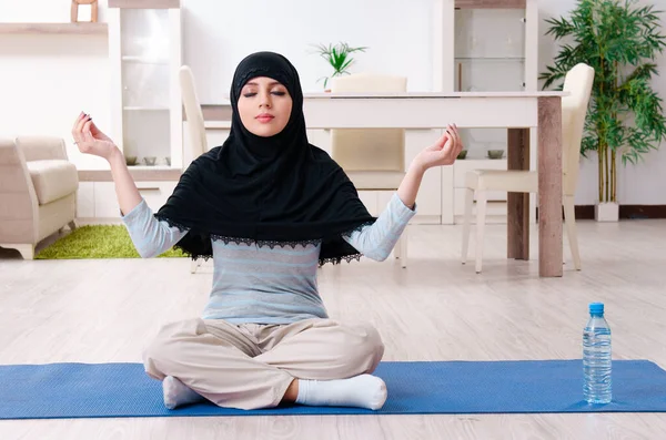 Молодая женщина в хиджабе делает упражнения дома — стоковое фото