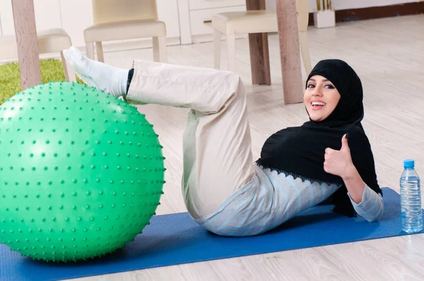 Mujer joven en hiyab haciendo ejercicios en casa —  Fotos de Stock