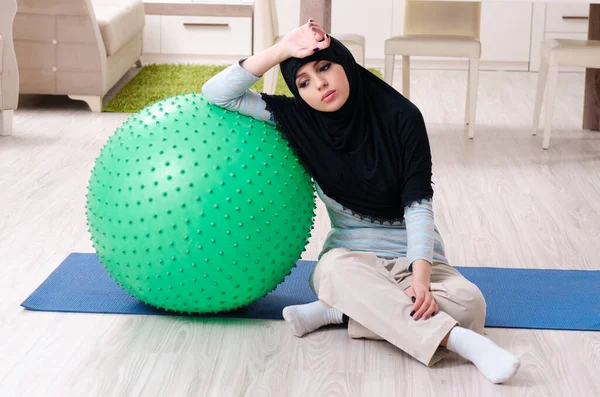 Mujer joven en hiyab haciendo ejercicios en casa —  Fotos de Stock