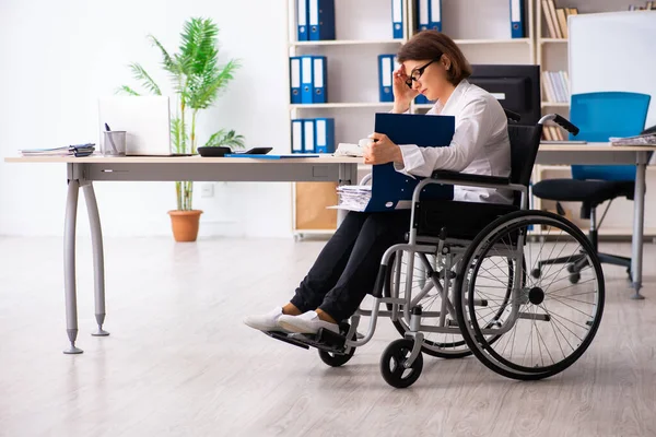 Ofisteki tekerlekli sandalyedeki kadın çalışan. — Stok fotoğraf
