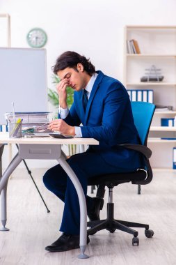 Genç işadamı ofiste oturuyor ve çalışıyor.