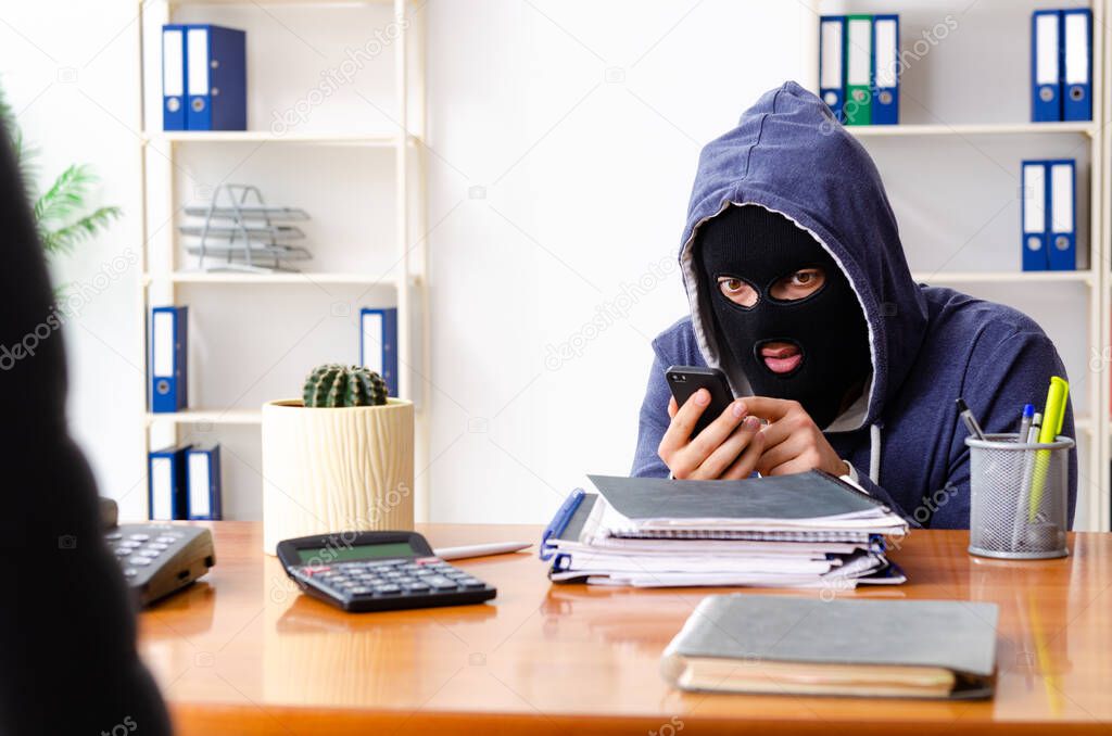 Male thief in balaclava in the office