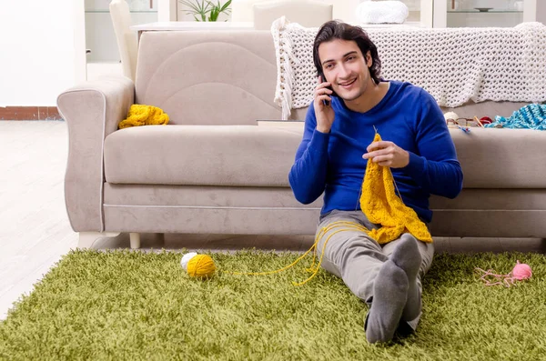 Young good looking man knitting at home