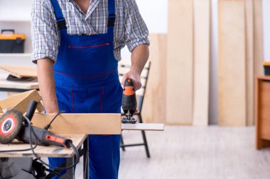 Genç erkek marangoz içeride çalışıyor.