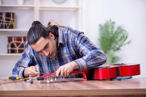 Junger gutaussehender Reparateur repariert Gitarre — Stockfoto