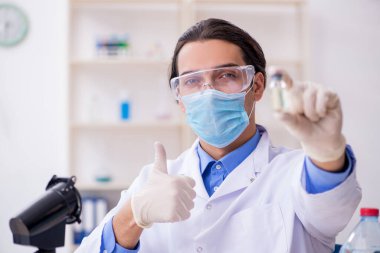 Genç erkek kimyager laboratuarda deney yapıyor.