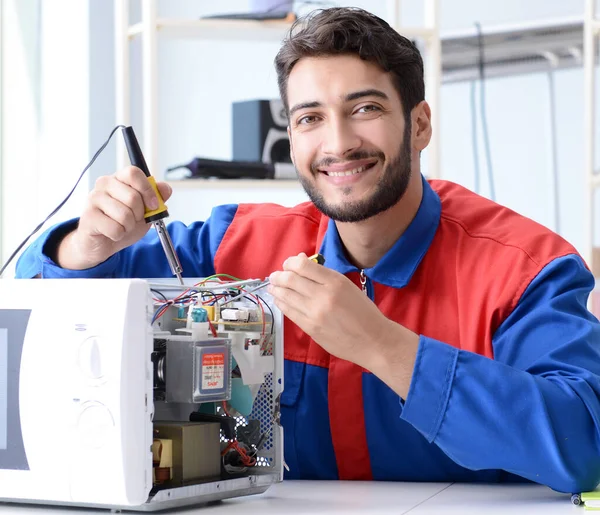 Young repairman fixing and repairing microwave oven — Stock Photo, Image