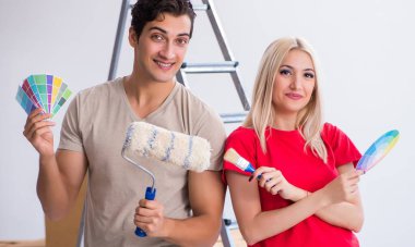 Ev tadilatı sırasında genç bir aile boya işi yapıyor.