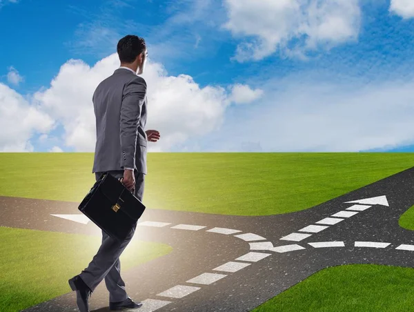 Young businessman at crossroads in uncertainty concept — Stock Photo, Image