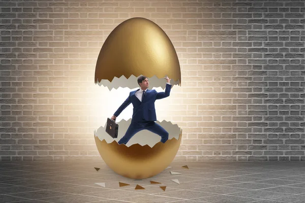 Businessman breaking out of golden egg — Stock Photo, Image