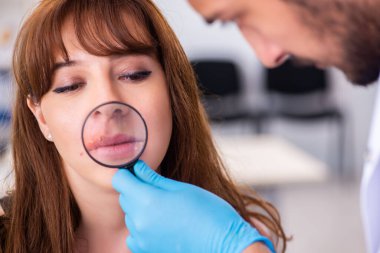 Genç bir kadın erkek doktor dermatoloğunu ziyaret ediyor.