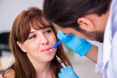 Genç bir kadın erkek doktor dermatoloğunu ziyaret ediyor.