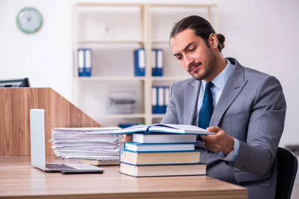 Ung manlig affärsman läser böcker på arbetsplatsen — Stockfoto