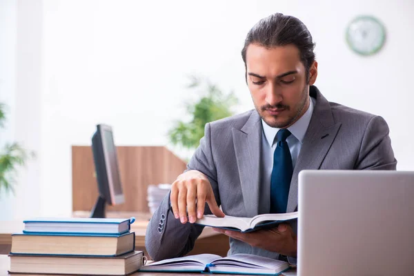 Joven hombre de negocios leyendo libros en el lugar de trabajo — Foto de Stock