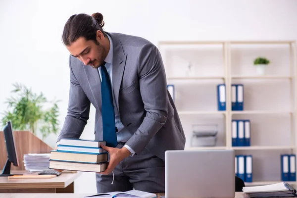 Ung manlig affärsman läser böcker på arbetsplatsen — Stockfoto