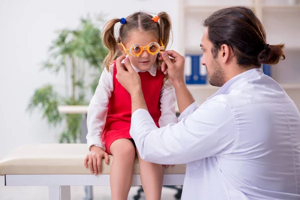 Menina pequena visitando jovem médico oculista masculino — Fotografia de Stock