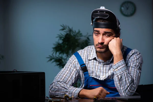 Joven técnico masculino reparando el ordenador en el taller por la noche — Foto de Stock