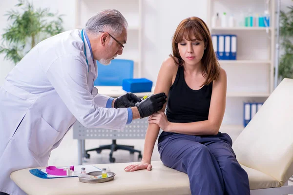 Jonge vrouw bezoekt oude mannelijke arts — Stockfoto