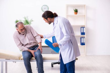 Yaşlı hasta genç erkek doktoru ziyaret ediyor.