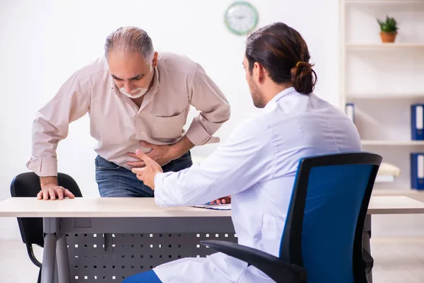 Old patient visiting young male doctor — Stock Photo, Image