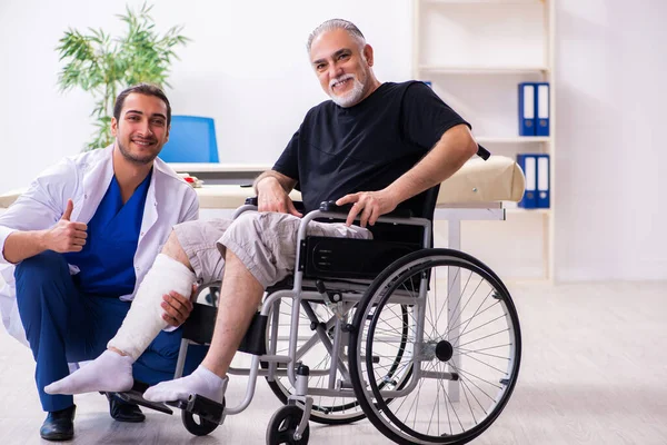 Viejo hombre herido visitando joven médico traumatólogo —  Fotos de Stock