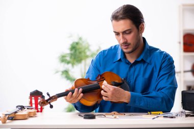 Kemanı tamir eden genç bir erkek tamirci