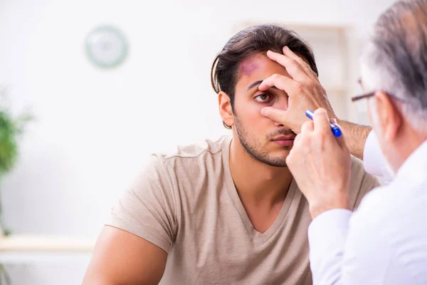 Jovem rosto ferido homem visitando experiente médico traumato masculino — Fotografia de Stock