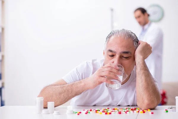 Joven médico masculino visitando a viejo paciente masculino en casa — Foto de Stock