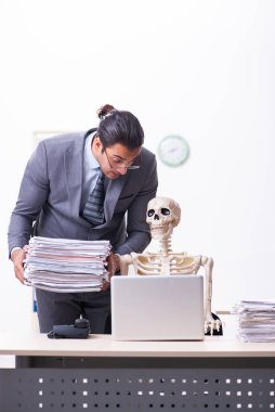 Genç erkek çalışan ve iskelet ofiste.