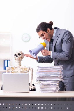 Genç erkek çalışan ve iskelet ofiste.