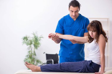 Yaralı kadın genç erkek doktor osteopat 'ı ziyaret ediyor.