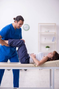 Yaralı kadın genç erkek doktor osteopat 'ı ziyaret ediyor.