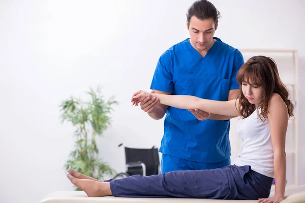 Skadad kvinna besöker ung manlig läkare osteopat — Stockfoto
