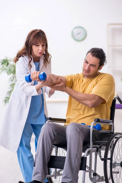Young male patient in wheel-chair doing physical exercises — Stock Photo, Image