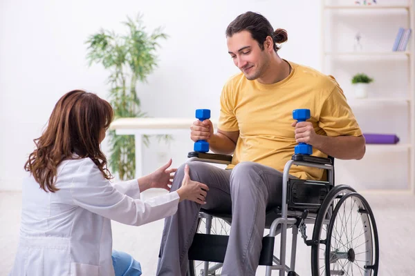 Young male patient in wheel-chair doing physical exercises — Stock Photo, Image