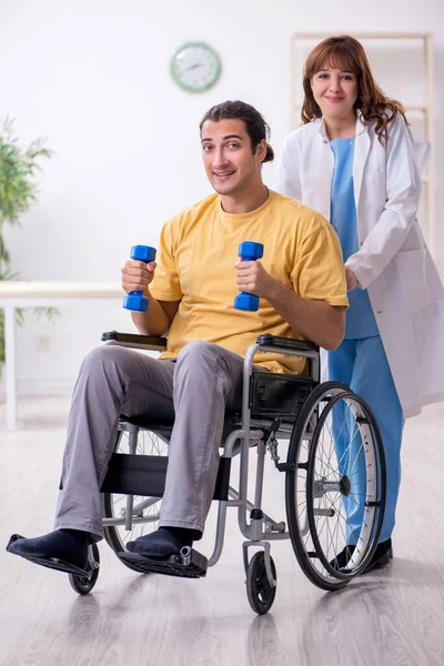 Junge männliche Patientin im Rollstuhl macht körperliche Übungen — Stockfoto