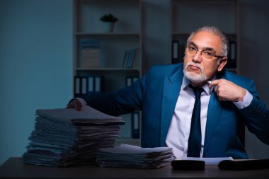 Eski erkek çalışan ofiste geç saatlere kadar çalışıyor.