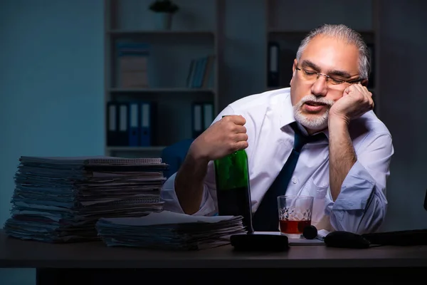 Oude mannelijke werknemer die laat op kantoor werkt — Stockfoto