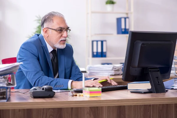 Velho empregado masculino e excesso de trabalho no escritório — Fotografia de Stock