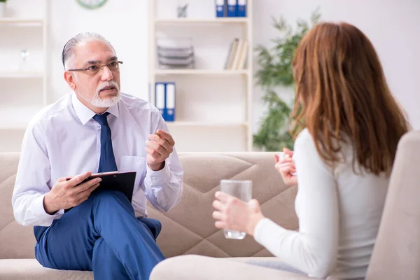 Jonge vrouw bezoekt oude mannelijke arts psycholoog — Stockfoto