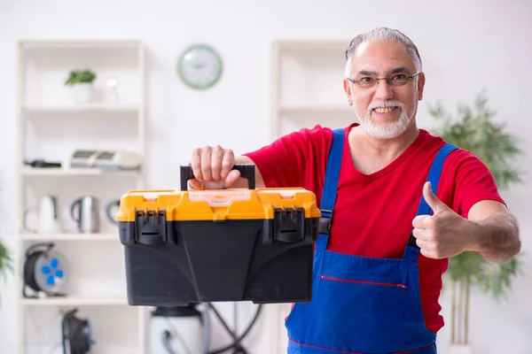 Oude mannelijke aannemer repareert huishoudelijke apparaten binnen — Stockfoto