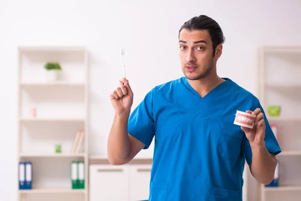 Jonge mannelijke tandarts werkzaam in de kliniek — Stockfoto